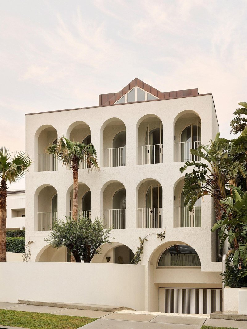 Street view of the white rendered facade with arched loggias and a gabled roof above