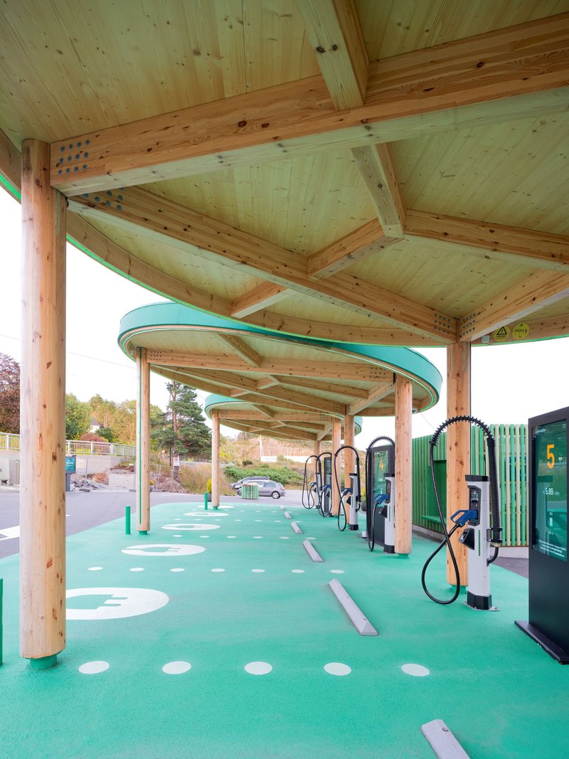 Underside view of the timber canopy structure showing exposed joinery and radiating beams over the charging stations