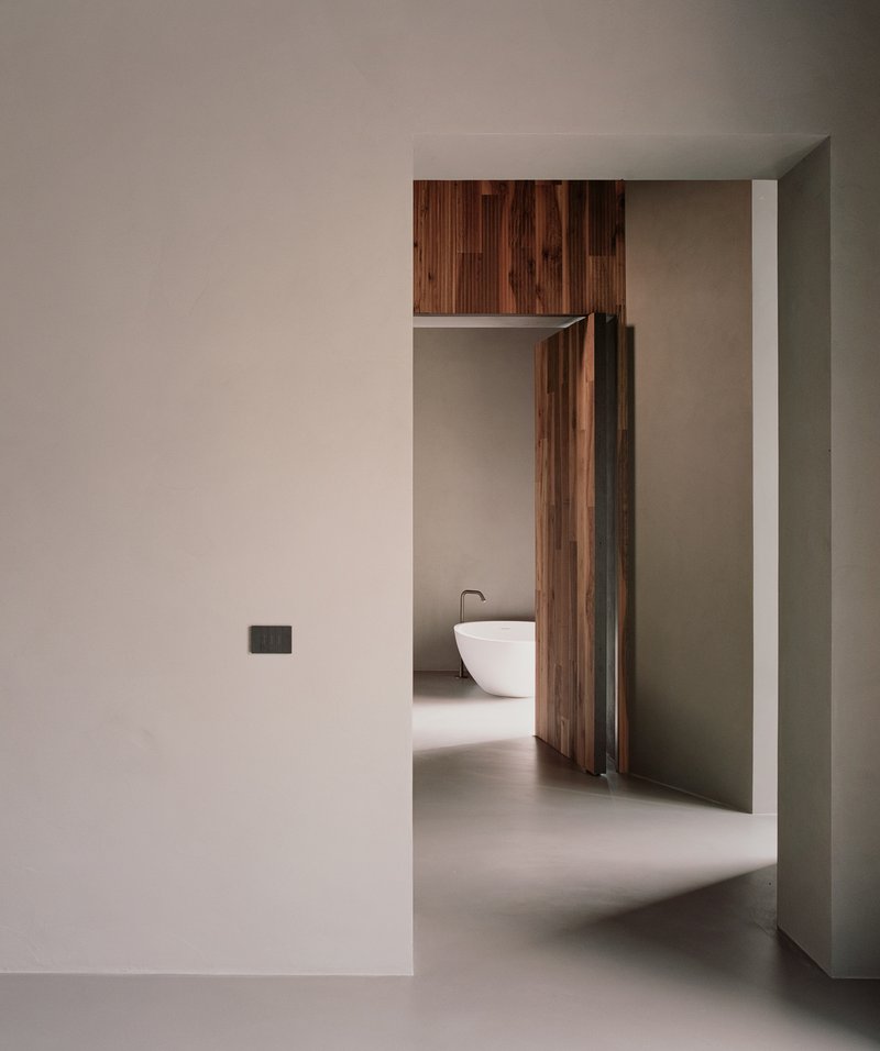 View through doorway into a bathroom with freestanding white tub and timber cabinetry