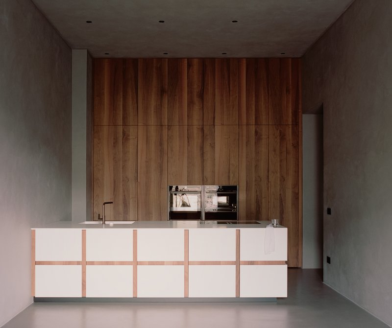 Kitchen island with white panels and timber detailing against a full-height wood cabinet wall