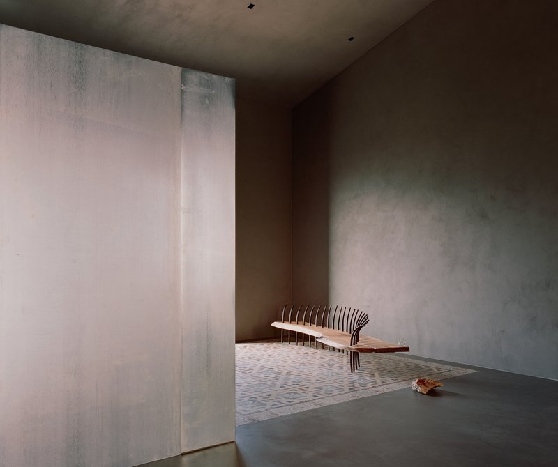 Interior room with slatted timber bench against rendered plaster walls with textured trowel marks