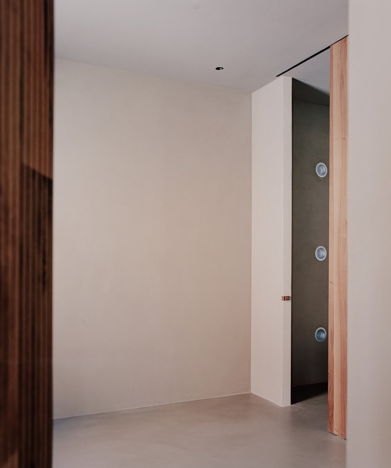 Timber-edged doorway opening into a dark corridor with three circular wall fixtures