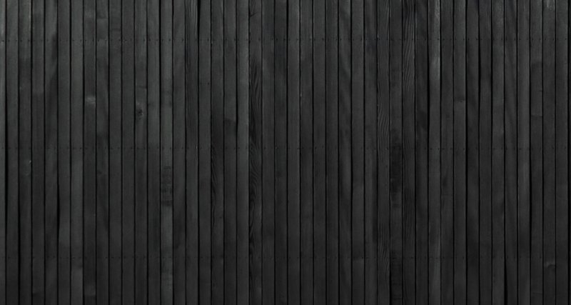 Close-up of vertical blackened timber cladding with fine parallel grooves