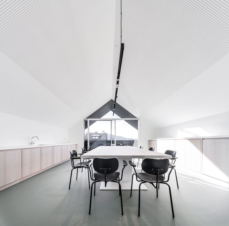 Vaulted dining space with perforated acoustic ceiling panels and gable window framing mountain view beyond