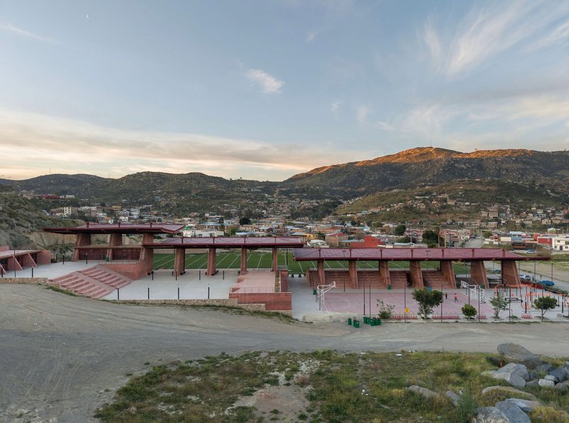 Distant view of the linear canopy structures spanning the athletic complex against hillside development