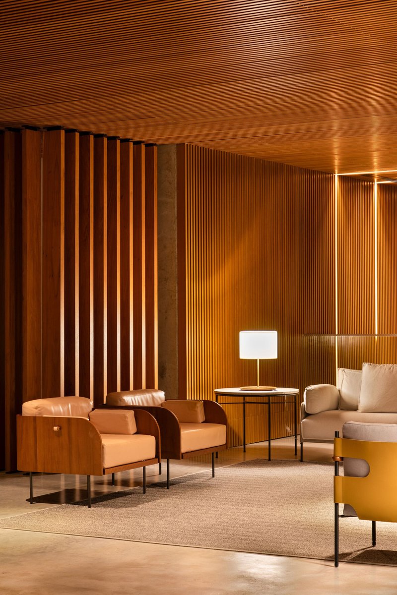 Interior lounge with vertical timber slat walls and slatted ceiling illuminated by warm evening light