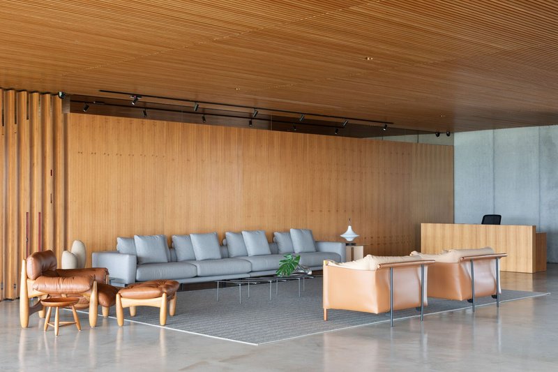Open lobby space with slatted wood ceiling and concrete reception desk between seating zones
