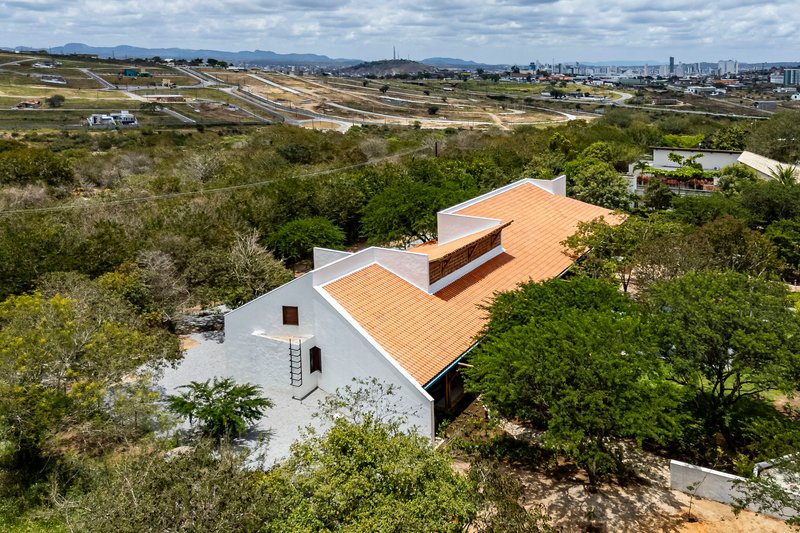 Elevated view of the terracotta tiled roof with protruding clerestory volume nestled among green trees