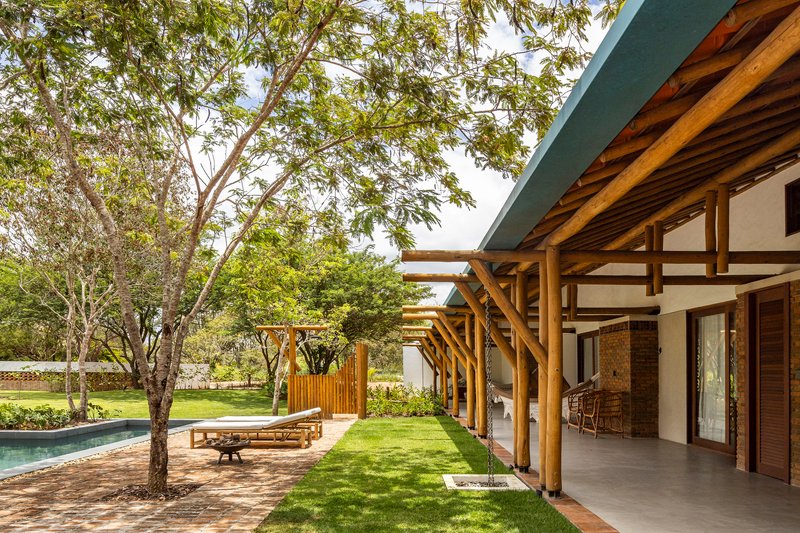 Covered porch with exposed timber beams and rafters overlooking a lawn shaded by mature trees
