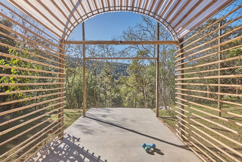 View through the barrel-vaulted timber pavilion with horizontal slats framing the wooded landscape beyond