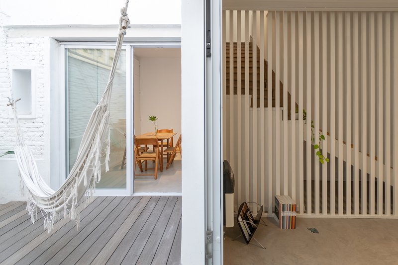 Timber courtyard deck with a hammock hung beside a vertical wood slat screen framing the interior view
