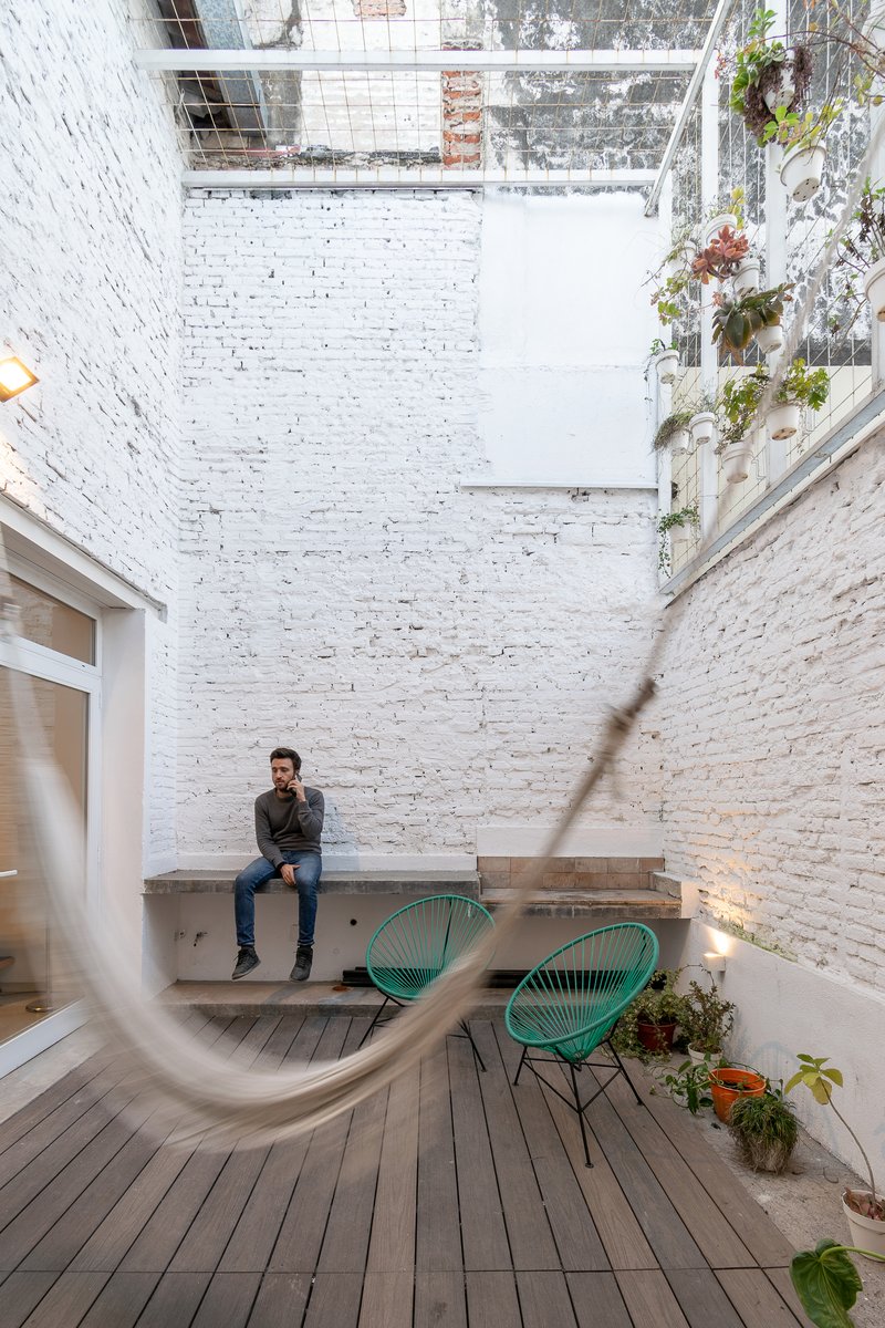 Courtyard with white-painted brick walls, timber deck, planted skylight and a seated figure