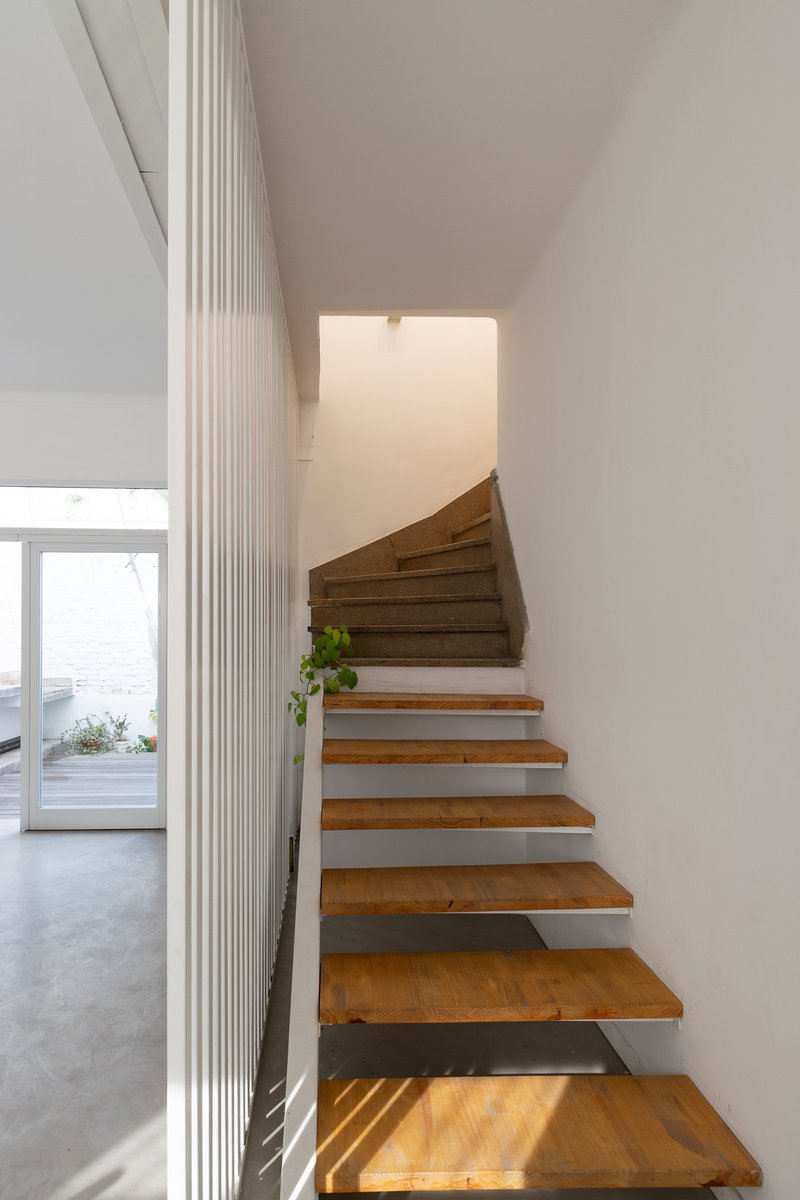 Floating timber staircase with steel stringers ascending between white fluted wall panels