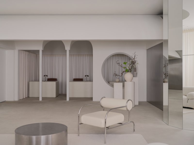 White arched niches with draped curtains and display plinths beneath a pale vaulted ceiling