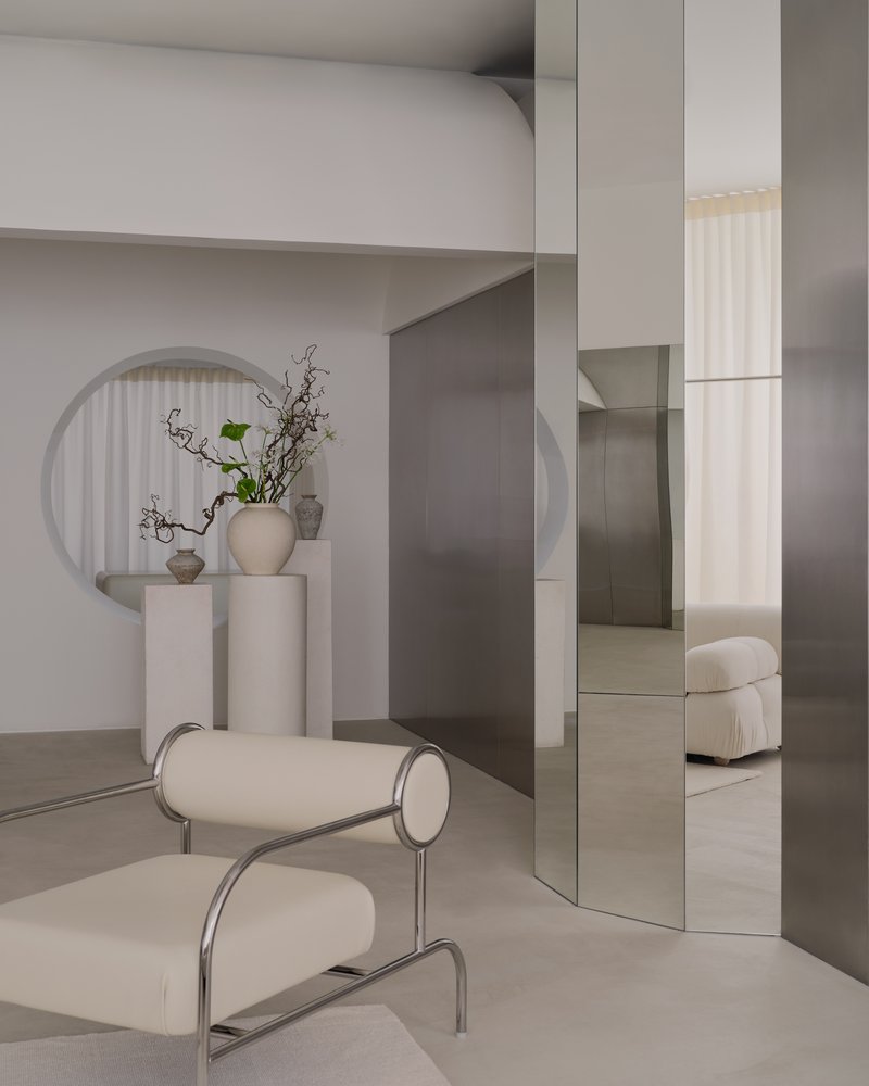 Tubular steel lounge chair in front of mirrored column and circular wall niche with fluted curtain