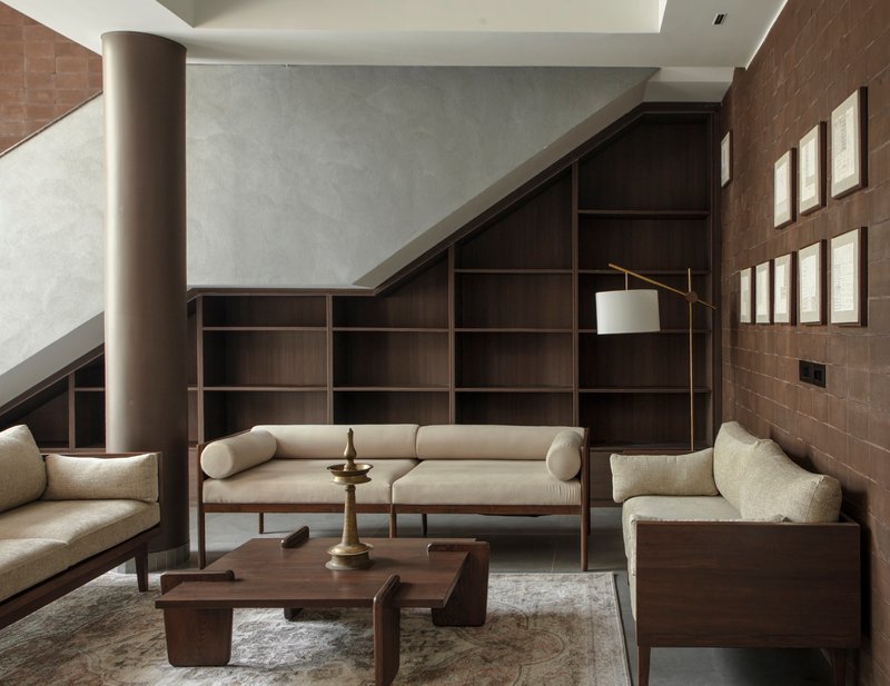 Double-height living room with dark wood shelving beneath an angled skylight and cylindrical column