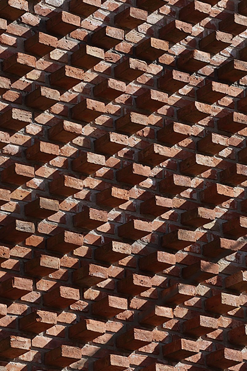 Detail of diagonal brick pattern with deep shadows cast by projecting units