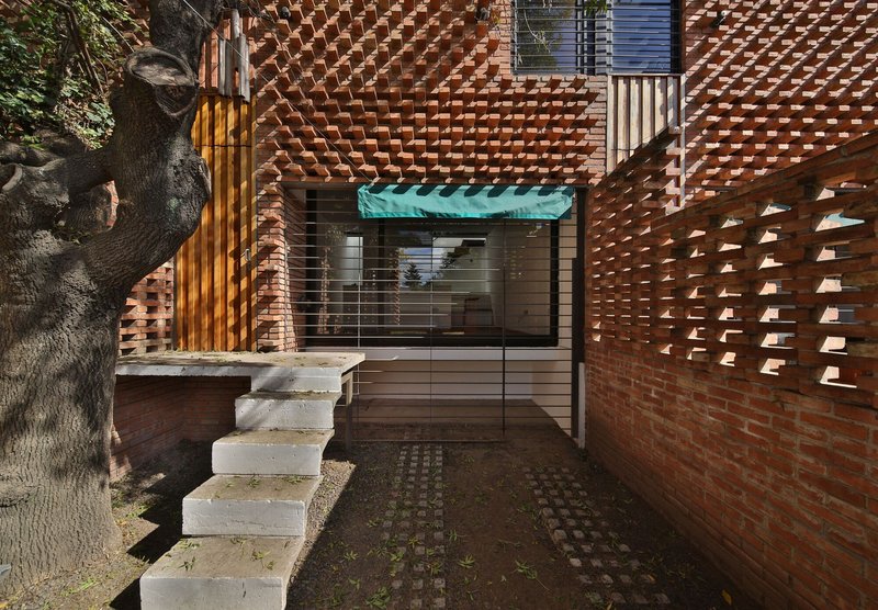 Courtyard entry with patterned brick walls and concrete steps flanked by an old tree