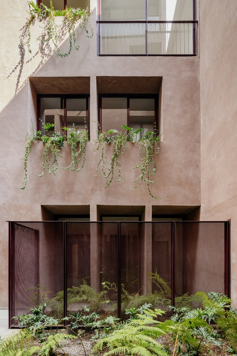 Interior facade showing planted window boxes with trailing greenery and perforated metal panels below