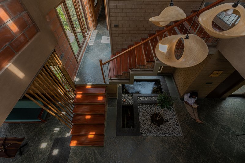 Overhead view of the timber staircase with integrated lighting descending past the interior courtyard with water feature