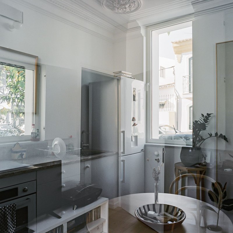 White kitchen interior with ornate ceiling medallion and tall windows overlooking neighboring buildings