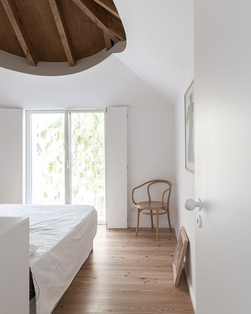 Bedroom with octagonal timber ceiling vault and glazed doors opening to greenery outside