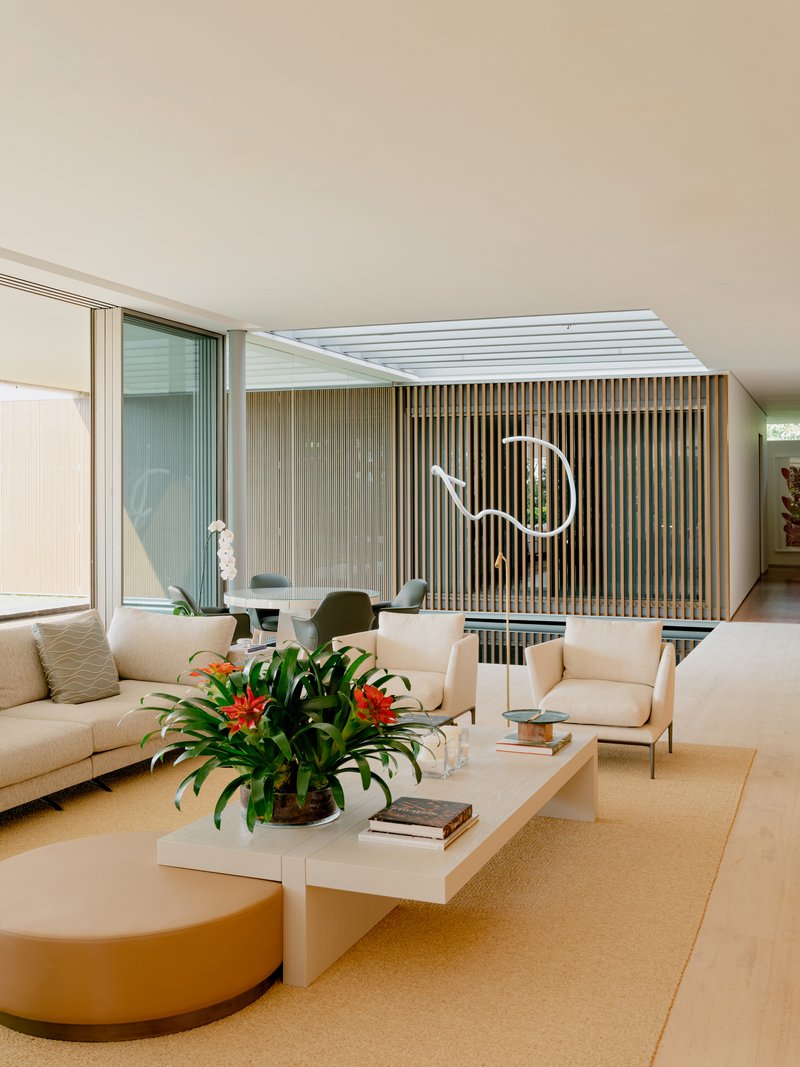 Living area with timber screen, reflecting pool, and neon wall sculpture in soft afternoon light