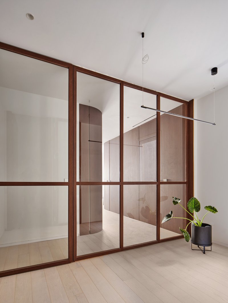 Timber-framed glass partition with pendant light and planters visible beyond the glazing
