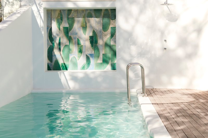 Courtyard pool with tiled mural and timber decking in dappled sunlight