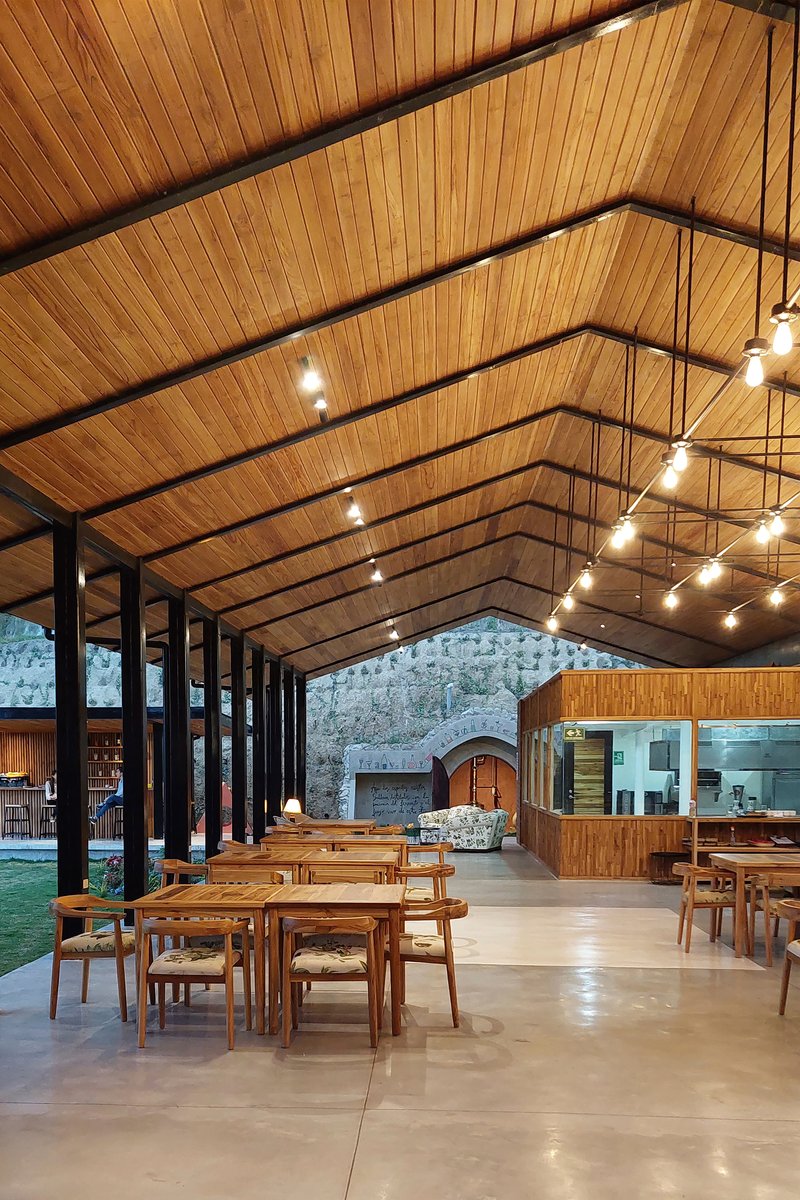 Dining hall with gabled timber ceiling, steel columns and string lights above timber tables