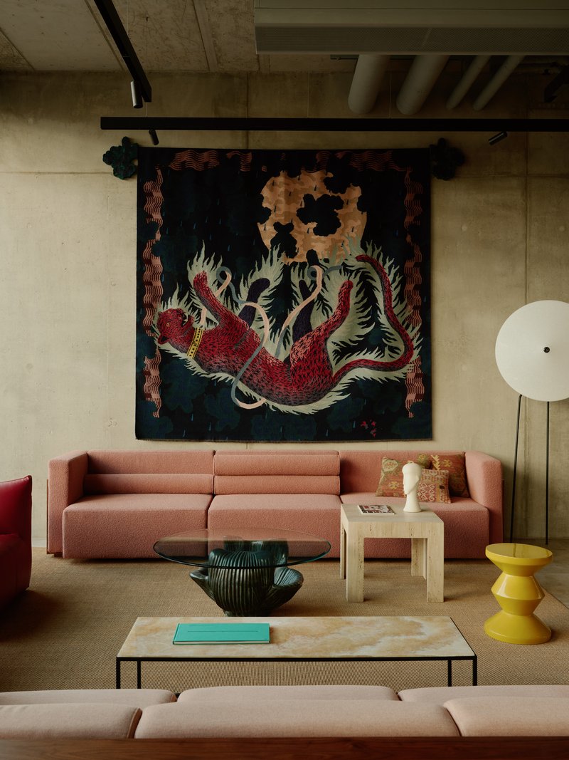 Close-up of seating beneath the dragon tapestry with exposed concrete ceiling and track lighting
