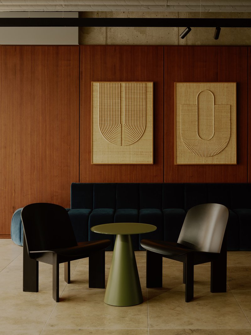 Seating nook with upholstered banquette, cone table, and two woven textile panels on walnut wall