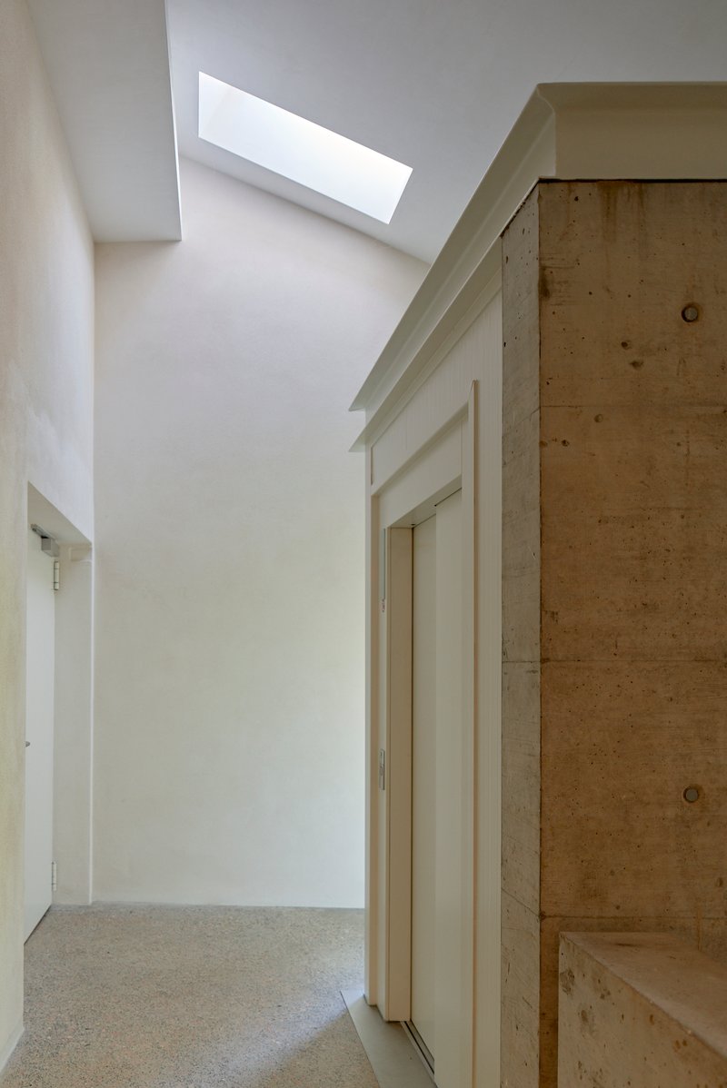Interior hallway with plywood built-in storage and rectangular skylight casting daylight on white walls