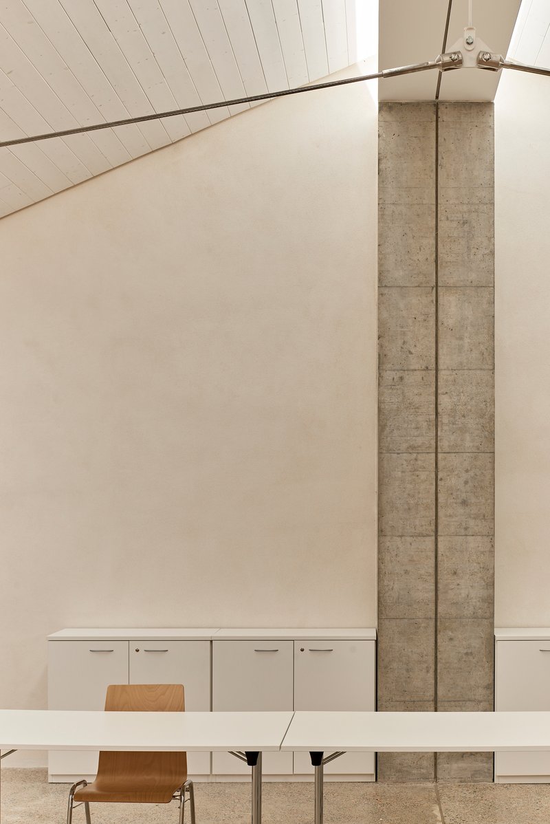 Dining area with exposed concrete column beside white cabinets under a timber slat ceiling