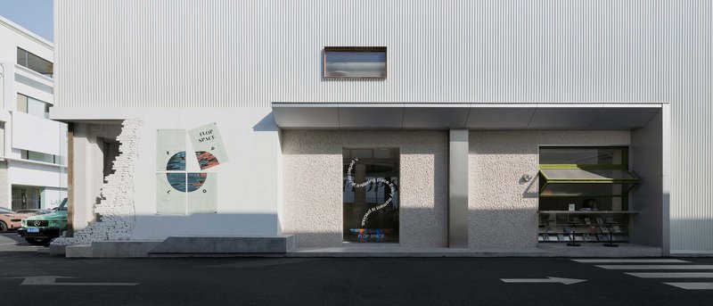 Ground level facade showing exposed brick wall fragments alongside grey stucco panels and storefront openings