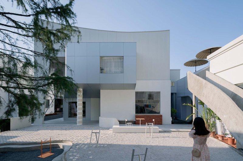 Courtyard view of the layered facade with tree branches in foreground and visitor photographing the entrance