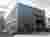 This architectural image showcases an industrial warehouse building with a metal-clad exterior and a