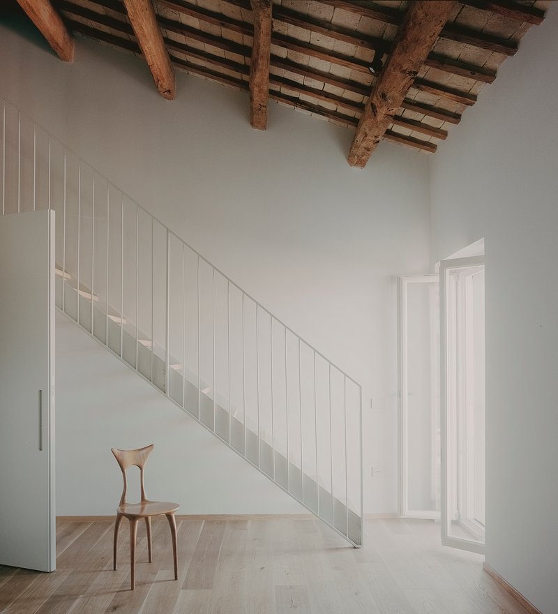 Interior staircase beneath exposed timber beams and terracotta tile ceiling with diffused natural light
