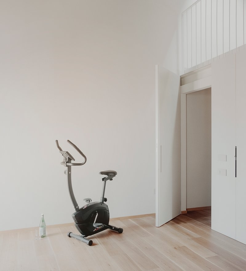 White-walled room with an exercise bike on light wood flooring near a doorway opening