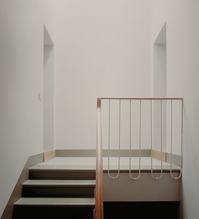 Steel rod balustrade with timber handrail at the stair landing in a white interior