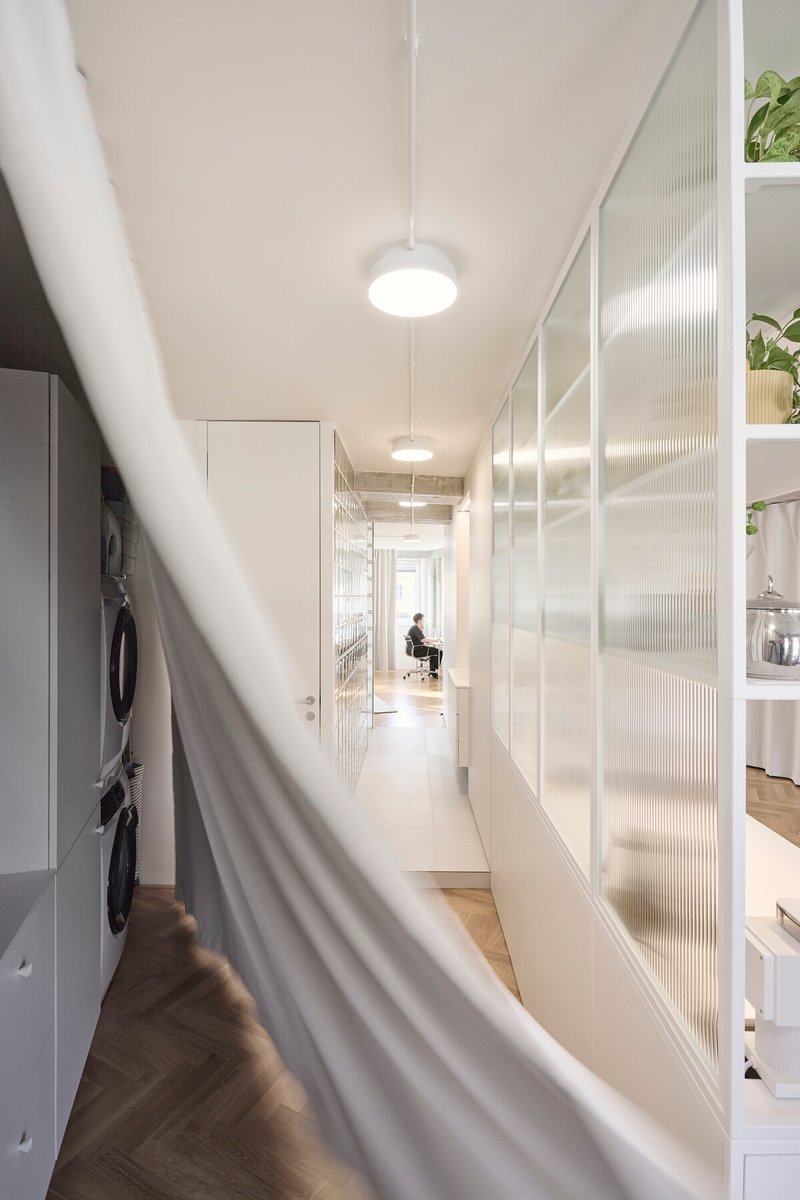 Long hallway view with translucent ribbed glass panels and white curtain in foreground