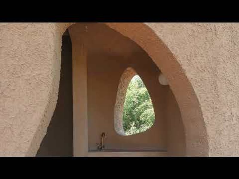 Vaulted niche with an organic shaped window opening framing green foliage beyond