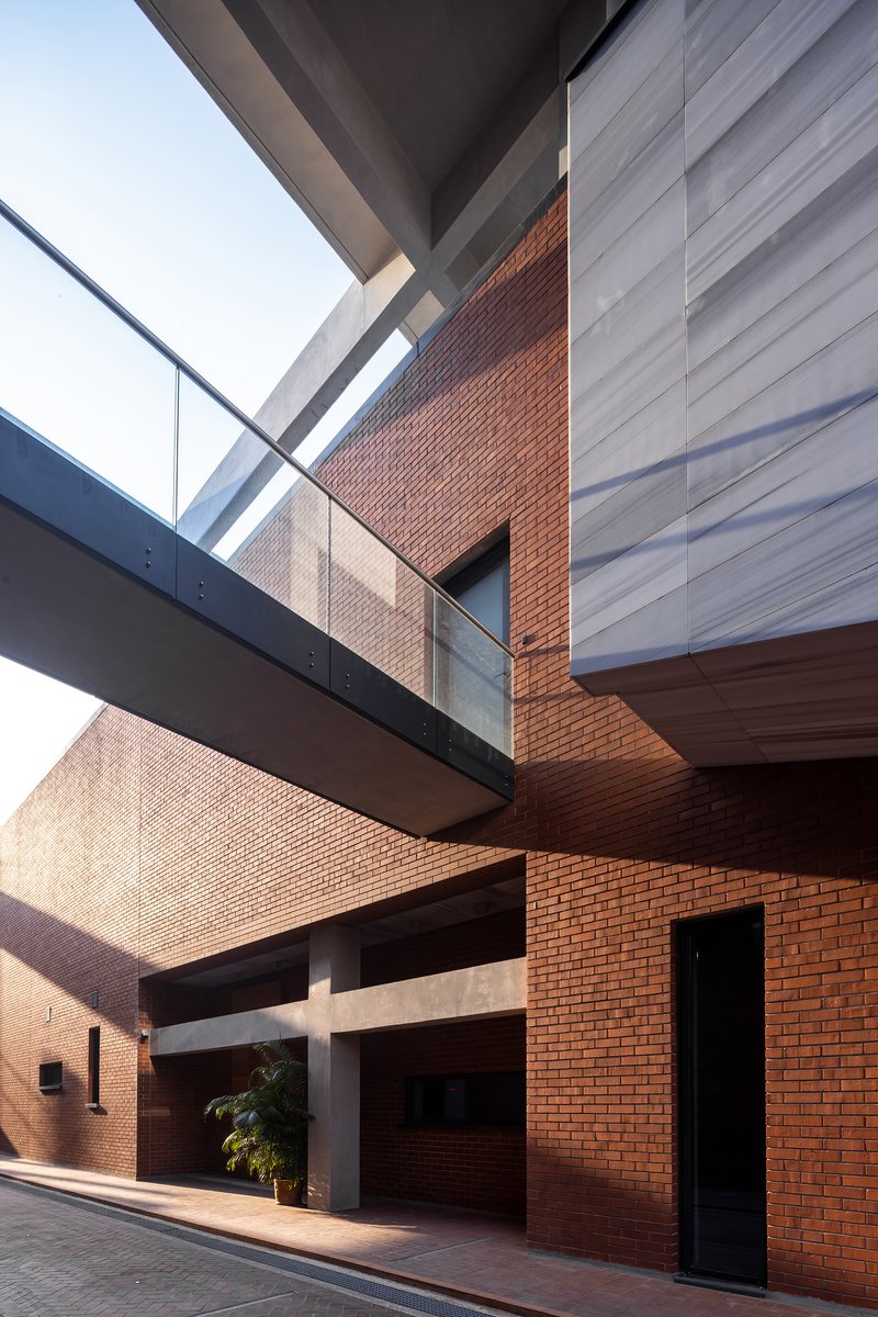 Interior courtyard with red brick walls crossed by horizontal concrete bridges and glazed openings above