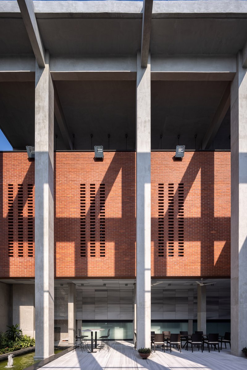 Perforated brick screen wall behind concrete columns casting sharp shadows in bright sunlight