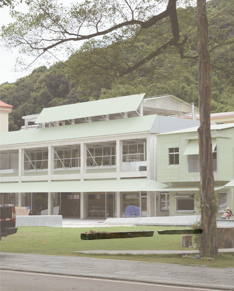 Two-story facade with exposed concrete columns and continuous ribbon windows facing a grass lawn with tree