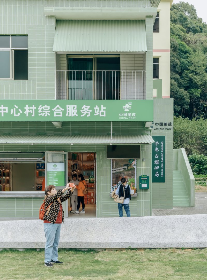 Green-clad storefront with canopy and signage as visitors gather at the entrance