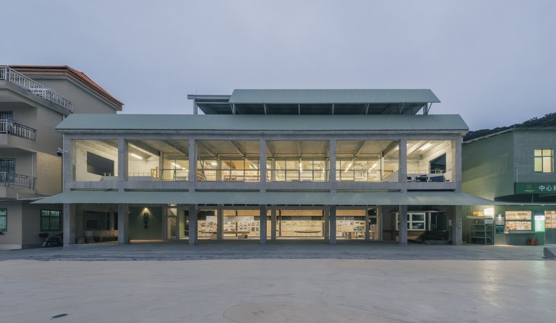 Front elevation showing the open ground floor colonnade and upper glazed volume beneath a metal canopy roof