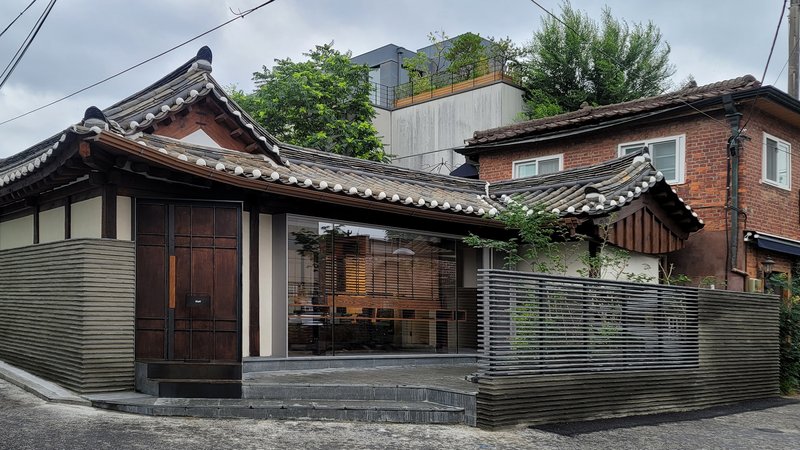 Street view of the entry facade with horizontal ribbed metal cladding and curved tile roof