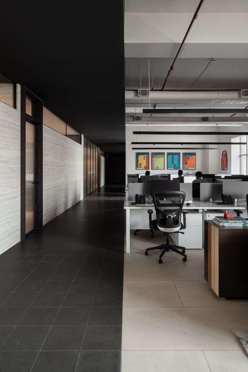 Open office floor with exposed ceiling ducts and workstations beneath colorful framed art