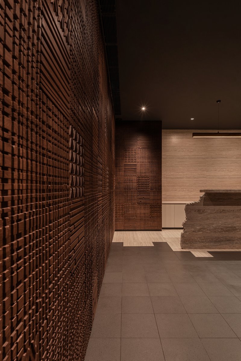 Corridor view along the basketweave timber wall with recessed doorway and spotlit ceiling